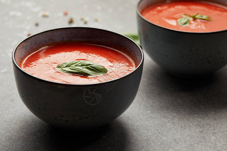 灰桌上放着美味番茄汤和罗勒的盘子图片