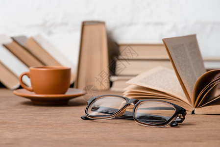 木桌上的眼镜咖啡和书籍的特写视图图片