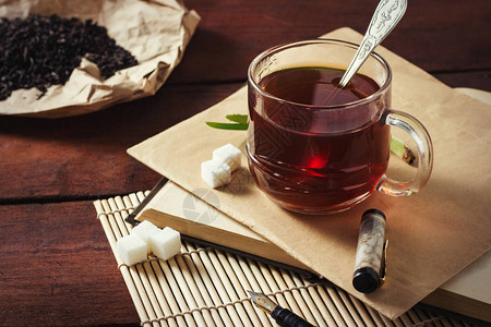 茶杯手工艺纸上的干茶叶糖切片信封和木背景图片