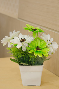 木桌上白色花瓶中的塑料花图片