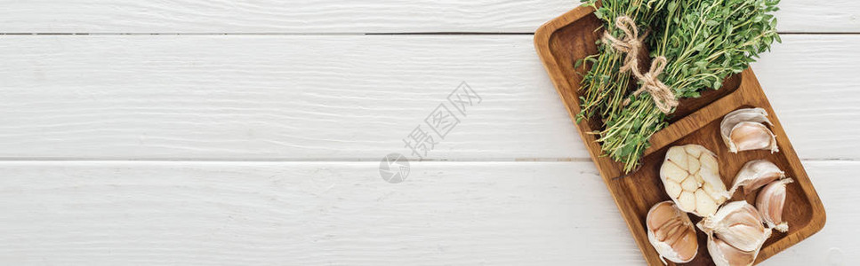 白色木桌上的蒜瓣和百里香木板全景拍摄图片