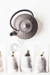 茶叶拍摄白色背景的灰色铸铁壶旁边酿制的一次过滤袋中的不同茶叶顶层背景