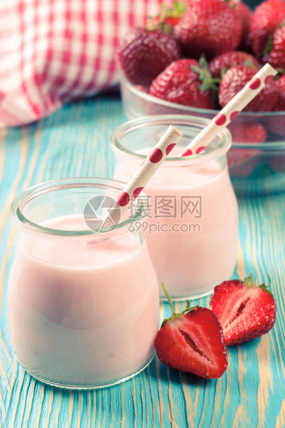 玻璃罐中的草莓奶昔在蓝木制桌边的蓝色木图片