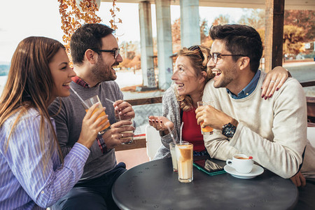 四个朋友一起开心喝咖啡的小组咖啡馆里的两个女人和两个男人谈笑着享图片