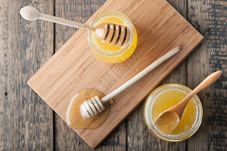两罐加蜂蜜双层和木勺在切割板图片