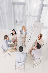 中年人坐在椅子上在集体治疗期间交谈的高角度视图片