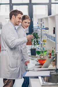 白大衣中的生物学家在实验室中与烧瓶试剂和柠图片