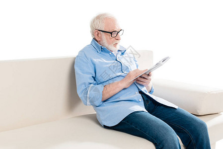 长胡子的老人在看书坐在沙发上白着孤立图片