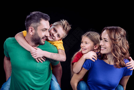 幸福的家庭在多彩的T恤衫中拥抱和看着彼此图片