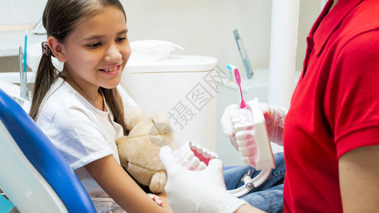 微笑的女孩在牙医办公室听关于牙齿卫生图片