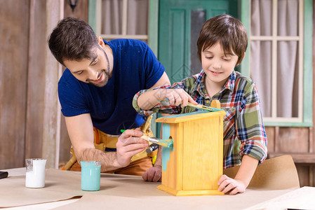 快乐的父亲和儿子一起画木制手图片