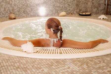 美丽的女人享受和放松在按摩浴图片