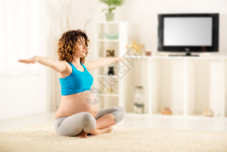 美丽的年轻孕妇在家锻炼图片