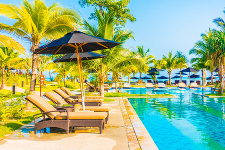 在酒店度假胜地的豪华户外游泳池周围保护伞和椅子图片