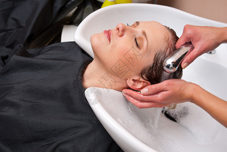 在美发沙龙洗女人头发的造型师图片