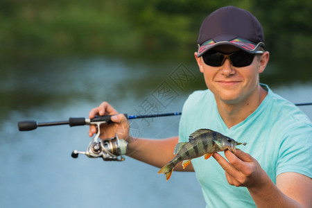 有人在河边钓到一条鱼带着眼镜和帽图片