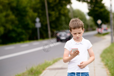 小男孩在街上用智能手机玩移动游图片