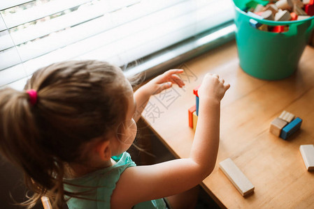 小女孩在窗边的儿童桌旁玩积木图片