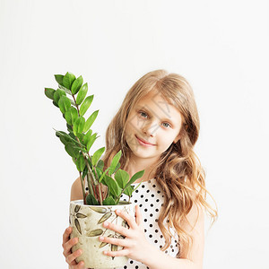 一个可爱的小女孩的肖像带着白色背景的绿植图片