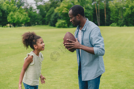 非洲裔美国人和小女儿在公园踢美式足球前图片