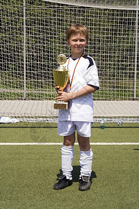 身着足球服的年轻男孩为杯子感到骄傲他的足球队在锦标赛中赢图片