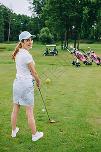带着高尔夫球杆站在高尔夫球场上的微笑女高尔夫图片