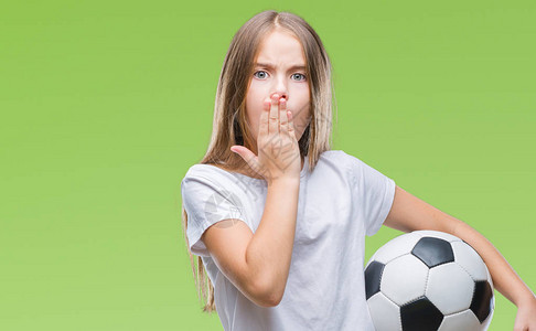 年轻漂亮的女孩拿着足球在孤立的背景上捂着嘴图片