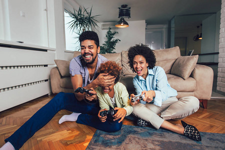 微笑的家庭坐在沙发上一起玩电子游戏图片