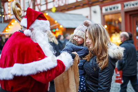 与母亲在圣诞市场上蹒跚学步的小女孩有趣的快乐孩子从圣诞老人的袋子里拿礼物假期圣诞节童图片
