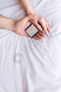 在床上持有避孕套的年图片