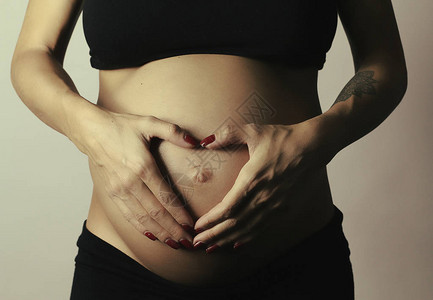 孕妇在婴儿乳房中握着她的双手图片