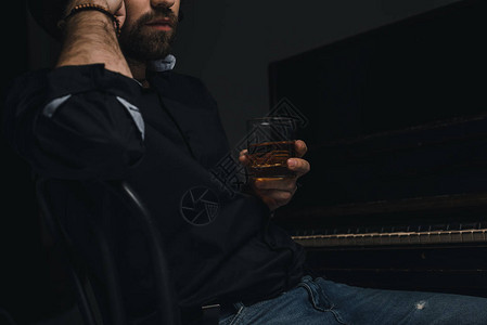 黑色的钢琴旁边坐着威士忌杯子的图片