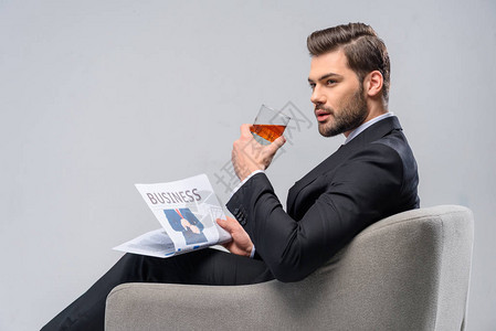 商人坐在手椅上带着报纸和威士图片
