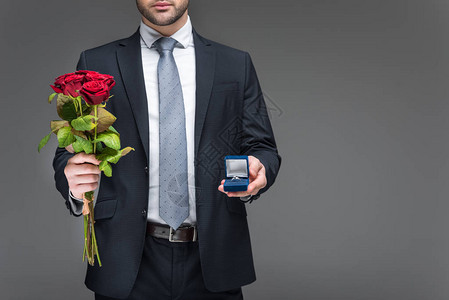 男人拿着一束红玫瑰和求婚戒指的剪影图片