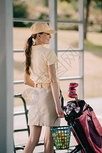 高尔夫球场携带高尔夫装备的马球和帽子上微笑图片