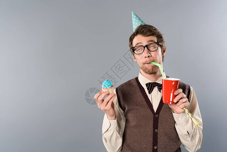 戴眼镜和帽子的男子带着纸杯蛋糕和喝苏打图片