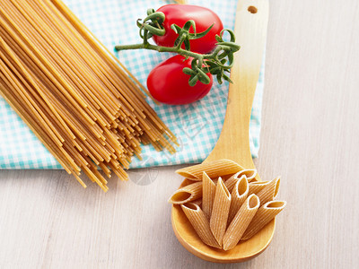 整面小麦意大利面和西红柿放在餐桌布图片