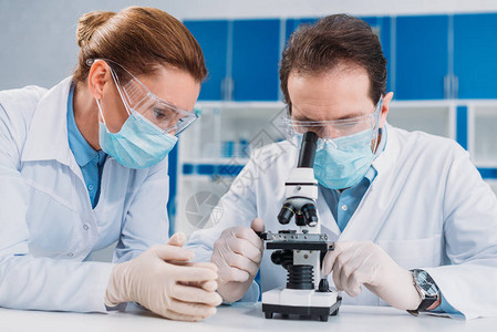 在实验室与显微镜一起工作的医学面罩和手套研图片