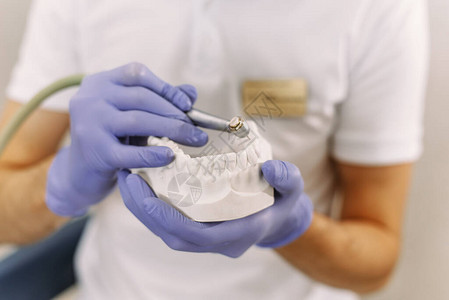 牙医拿着带有植入物的钻头在牙科治疗过程中牙科诊所患者牙齿使用的牙科钻图片