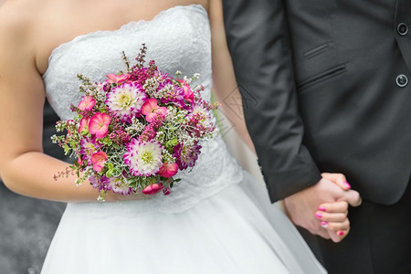 新婚夫妇手的细节与婚礼花束图片