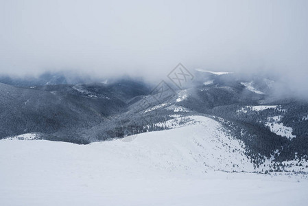 云层下的山势冬季风景和雪坡背景