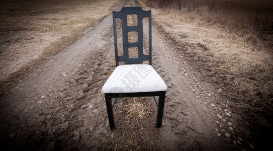 坐在土路中间的空椅子图片