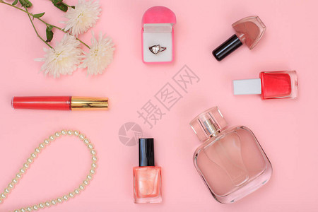 圆环盒珠子香水瓶指甲油瓶和粉红色背景的花朵图片