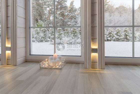 木屋内明亮的房间内部设有俯瞰冬季庭院的大窗户白色窗口中的白雪皑的冬季景观和花园图片