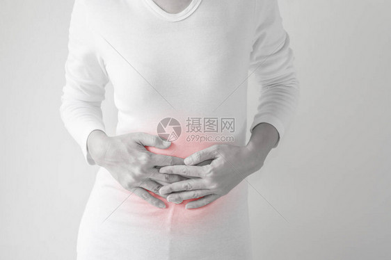 灰色墙壁背景上的中年妇女胃痛图片