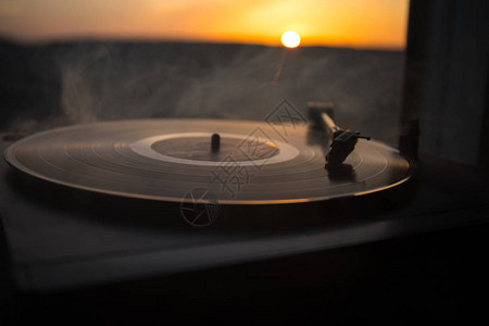 在山上日落的上的转盘黑胶唱片播放器DJ混合和播放音乐的声音技术胶唱片老式黑胶唱片播放器黑图片
