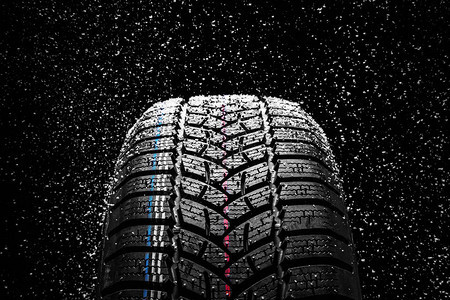 冬季汽车轮胎与黑色背景上的雪图片