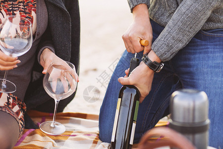 年轻快乐的情侣一起享受海滩野餐男人开酒图片