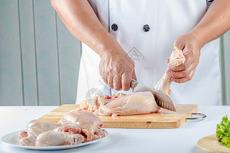 厨师用刀在厨房里切生鸡肉图片