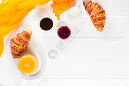 新鲜出炉的羊角面包橙汁果酱白色木制背景上的一杯黑咖啡法式早餐早上的新鲜糕点美味的甜点特写摄背景图片